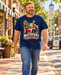 Man wearing Mayberry Barney's Sidecar T-Shirt – Navy walking on a Mayberry-inspired Main Street