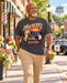 Man wearing Mayberry Andy Taylor Squad Car T-Shirt – Washed Gray walking on a Mayberry-inspired Main Street