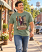 Man wearing Mayberry Otis Checks In T-Shirt – Sage Green walking on a Mayberry-inspired Main Street