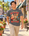 Man wearing What Happens in Mayberry Stays in Mayberry T-Shirt – Washed Gray walking on a Mayberry-inspired Main Street