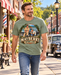 Man wearing Mayberry Father & Son Fishing T-Shirt – Sage Green walking on a Mayberry-inspired Main Street