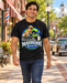Man wearing Mayberry Barney Fife Squad Car T-Shirt – Black walking on a Mayberry-inspired Main Street