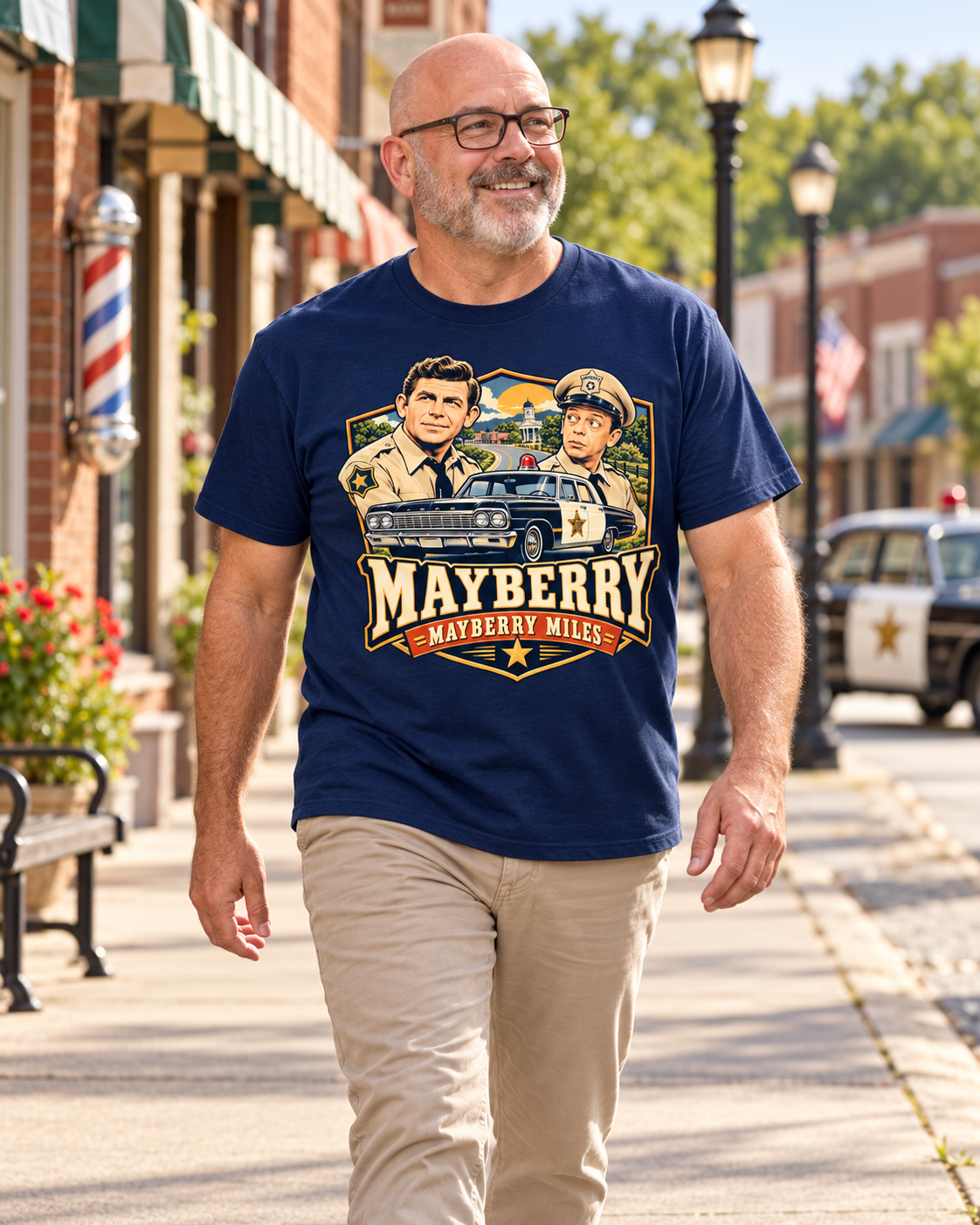 Man wearing Mayberry Miles Andy & Barney T-Shirt – Navy walking on a Mayberry-inspired Main Street
