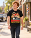 Man wearing Mayberry Barney Means Business T-Shirt – Black walking on a Mayberry-inspired Main Street