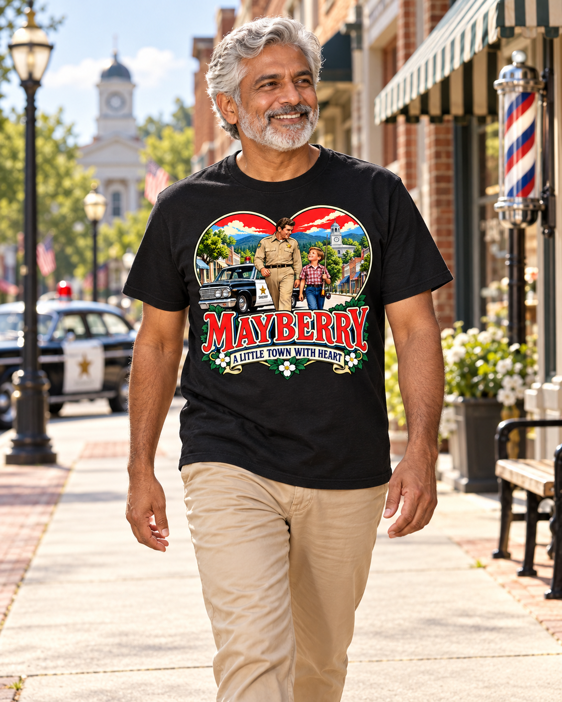 Man wearing Mayberry A Little Town with Heart T-Shirt – Black walking on a Mayberry-inspired Main Street