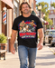 Man wearing Mayberry Goat on the Loose T-Shirt – Black walking on a Mayberry-inspired Main Street