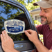 Man applying the Mayberry Original Hometown squad car sticker to his car's rear side window.